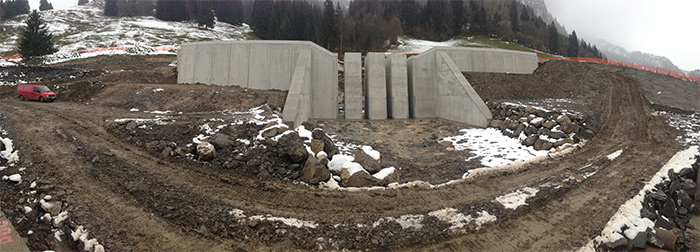 Im Bild ist eine Geschiebedosiersperre abgebildet, die am Talausgang des Jenbaches errichtet wurde. Zentral das Sperrenbauwerk aus Beton, Seitlich die Sperrenflügel mit Erdanschüttungen.