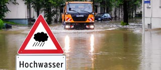 Warnschild Hochwasser vor überfluteter Straße Warnschild Hochwasser vor überfluteter Straße