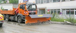 Lastkraftwagen schiebt Schlamm von der Fahrbahn Lastkraftwagen schiebt Schlamm von der Fahrbahn